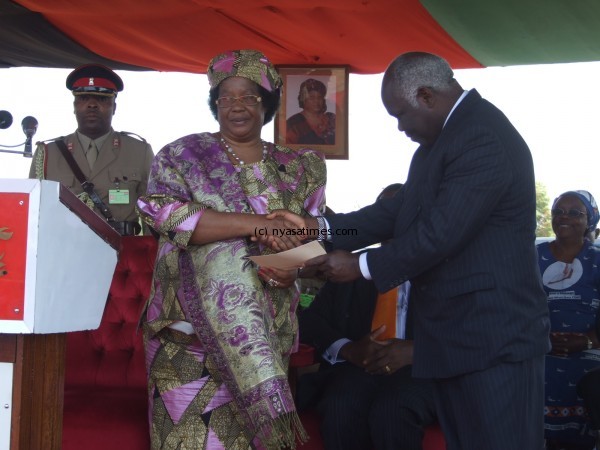 President Mrs Joyce Banda presenting a half million Kwacha cheque to Executive Director of the Bible Society of Malawi during t