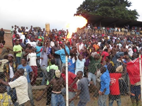 A Dedza fan blows up fire in celebration.