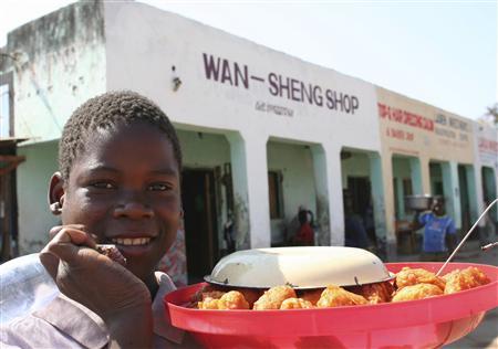 A Malawian hawker sells food outside a Chinese owned shop in Salima, a dusty town of 40,000 people near the shores of Lake Malawi, August 21, 2012. REUTERS/Ed Cropley