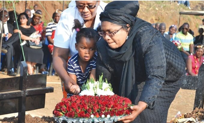 Mbendera’s wife Aida, and a grandchild being assisted to lay a wreath by Ella Tsukuluza, wife of bishop Charles Tsukuluza, founder of Revival Life Church