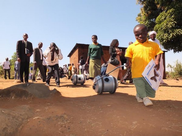 A beneficiary rolls his water barrel filled with water.