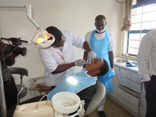 A dental therapist extracts a damaged tooth from a school girl
