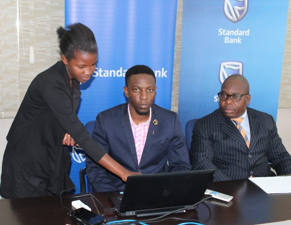 A journalist picking a lucky winner as Kazima (R) and Bank's Marketing officer look on