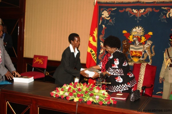 A member of MCTU presents a gift of books to President Joyce Banda