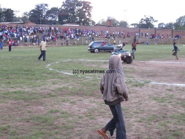 A vehicle and motorcycle drive along the pitch during celebrations.