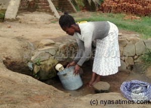 A woman drawing water from an unprotected well in Manja Township in Blantyre due to water scarcity- Photo by Lucky Mkandawire