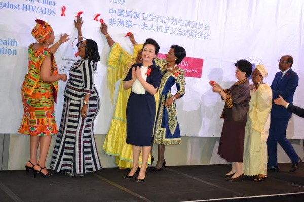 Africa's First Ladies attach red ribbons to express their gesture of commitment to the fight against AIDS during the HIV Advocacy event at the FOCAC summit. BY Gospel Mwalwanda