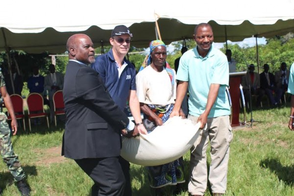 Agriculture Minister and Vanneste in cap presenting a bag of maize to a beneficiary.