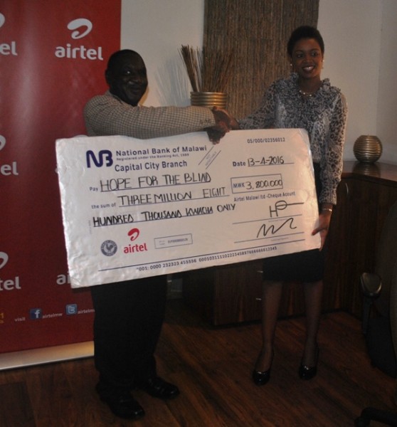Airtel Malawi's Corporate Social Responsiblity Manager Norah Chavula (R) hands over the cheque to Hastings Bwande of Hope for the Blind. Pic by Brian Itai,