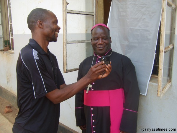 An official (left) shows the Bishop how the picture has come out.