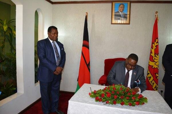 Attention: Chaponda looks on as Mutharika sings visitors book