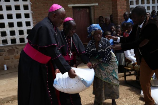 Bishop Msusa & Mtumbuka handing over a bag of maize to a flood victim.J