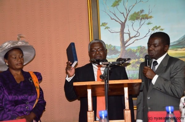Brown James Mpinganjira being sworn in as new Irrigation and Water Development Minister in President Banda's Government as his wife looks on