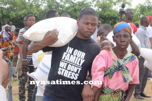 Bushiri helps an old woman carry her maize bag he donated