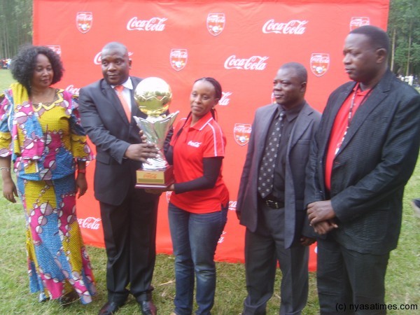 Carlsberg Malawi's Gwyneth Mchiela in red golf shirt presents the trophy to deputy education minister Chikumbutso Hiwa