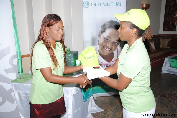 Carol Banda (left) receives a sample of the kit from Old Mutual official