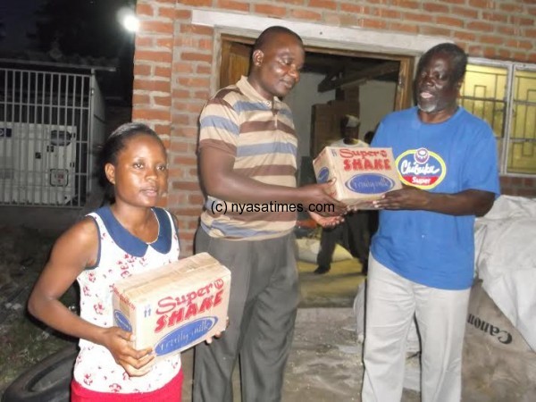 Chauluka (R) presents the symbolic items to Mtayamanya district disaster official another carton of the gifts.