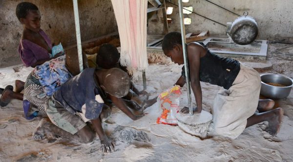 Children scavenge for maize floor at a maize mill in the hunger stricken southern district of Chikwawa. Photo: Thoko Chikondi