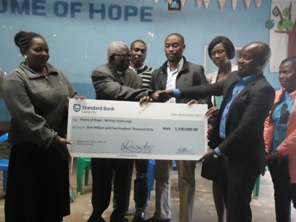 Chimenya (right) handing over the cheque to Chipeta (middle)
