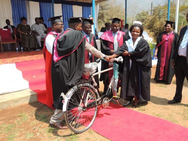 Chipungu flanked by Malasa and Minister Kumpalume handing over a bicycle to a best student.