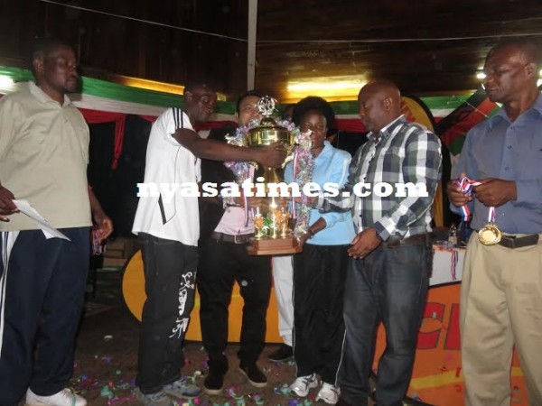 Dwangwa receive the trophy from Chiumia as Fam, Chipiku officials look on.