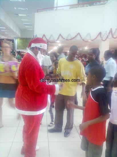 Father Christmas presenting a gift to a boy inside Chipiku Store