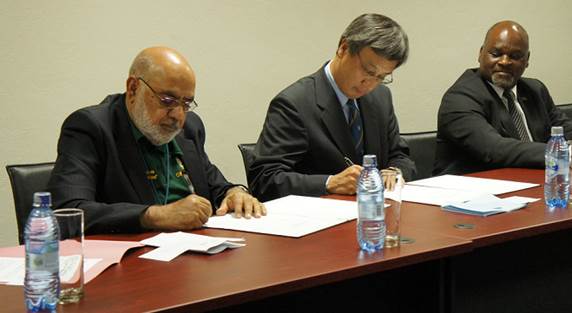 From left  Abdul Gaffar Jakhura and Shuichiro Nishioka signing the grant contract whilst  Chiyembekeza looks on