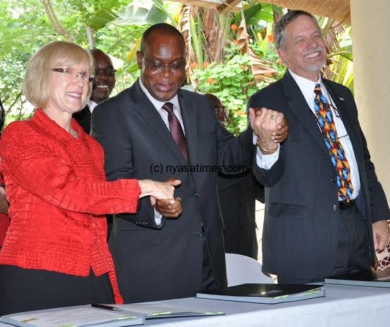 From left to right Ambassador Jeanine Jackson, Minister of Finannce Maxwell Mkwezala ... nd USAID Malawi Country Rep Doug Arbuckle hold hands after signing the agreement