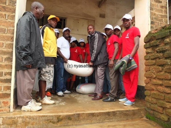 Sumaili and Group Village Headman Chilobwe in a symbolic handover of the donation as YOMODE members and some of the victims look on
