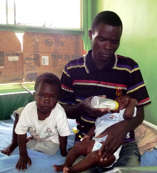 Jickson feeds his surviving baby beside him is his four-year-old son  - Pic. By Kondwani Magombo