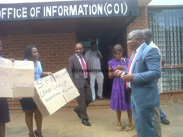 Journalists led by Rabecca Chimjeka hold a protests as Director of Information Mtumodzi looks on