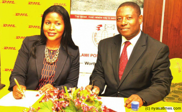 Malawi Post Master General, Andrew Kumbatira and DHL Malawi Director, Sarah Kayongo exchanging a signed deal