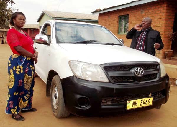 Kabwinja attends to a phone call as his wife stands beside their D4D Toyota Hilux pickup