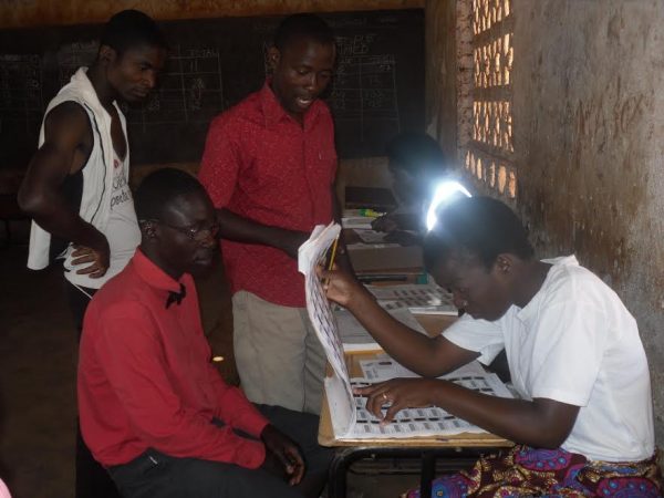 MEC clerk Linda Lungu checking names of disable men in voter roll book.