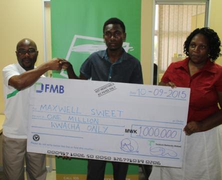 Mbekeani handing over a dummy cheque to Maxwell while Trophina Limbani looks on