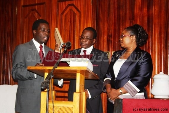 Justice Mackson Mbendera SC taking his oath presided over by Acting High Court Registrar Micheal Tembo, right, watching is Mrs Mbendera.