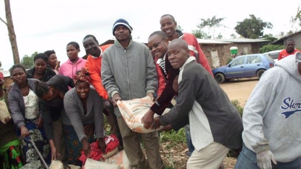 Mlogera in sun glasses and block leader Gondwe holding a cement bag launch bridge project