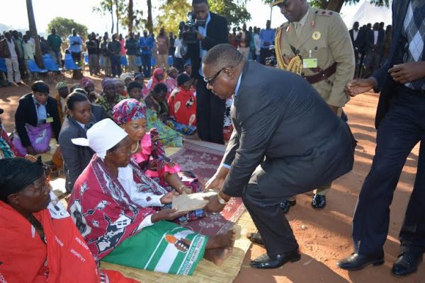 President Mutharika giving the wife of TA Njolomole a brown envelope containing cash to console her