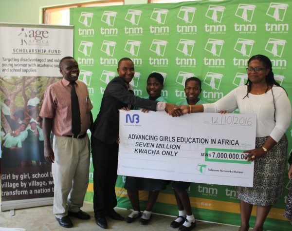 mwamadi-presenting-a-cheque-to-kwabwazi-while-st-marys-seconary-school-headmaster-and-some-beneficiaries-look-on
