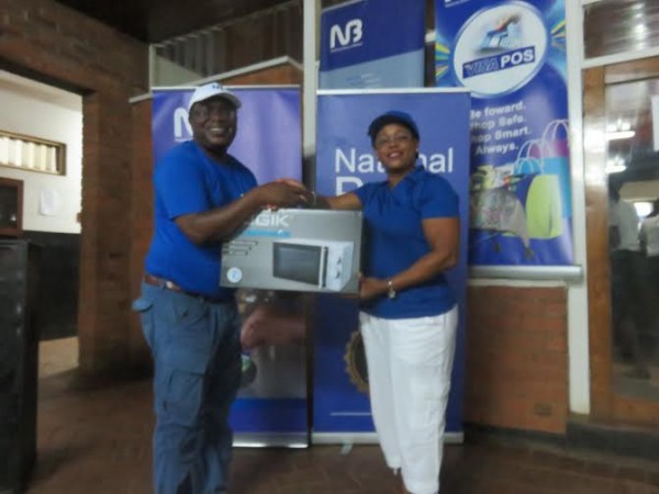 NB's Wilkins Mijiga presents a prize to Regina Mwanza