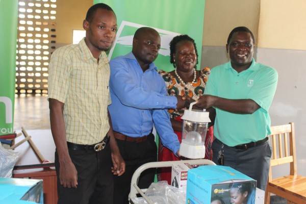 Nyirenda handing over  a solar lamp to TA Nthiramanja as In-Charge Chimongo ( far left ) and Group Village Head Chonde  look on