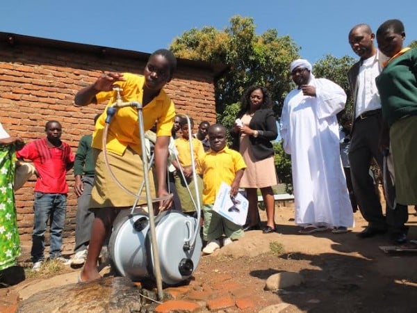 One of the beneficiaries demonstrates how the water barrels work
