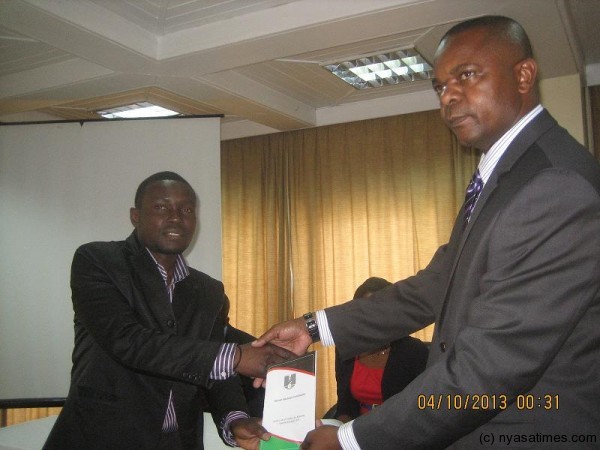 Potani (R) handovers a media code of ethics book to Lucky Mkandawire of Nyasa Times at Mzuzu Hotel /-Friday-