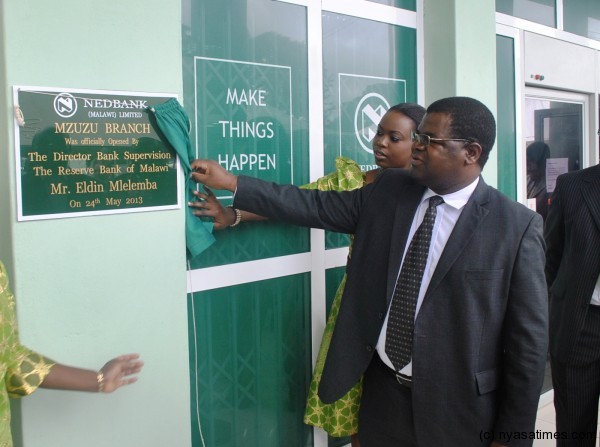 Reserve Bank of Malawis diorector of banking and supervision,Eldin Mlelemba(centre),officially unveiling a plaque at the opening of the Nedbank branch in Mzuzu