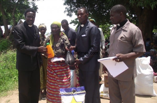 Rev Mwakibinga (left), handing over some of the relief items to an elderly lady. Pic by Pius Nyondo -- Nyasa Times. (1)