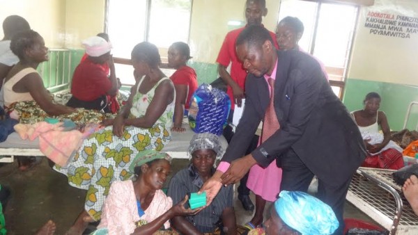 Rev. Kanjirawaya presenting tablets of soap to the mother of a newly born baby