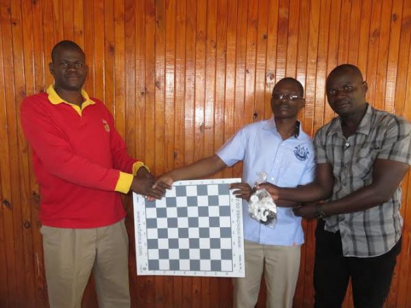Sharra (in red) hands over one of the sets to Chindole and CRCL official Leonard Mbwana