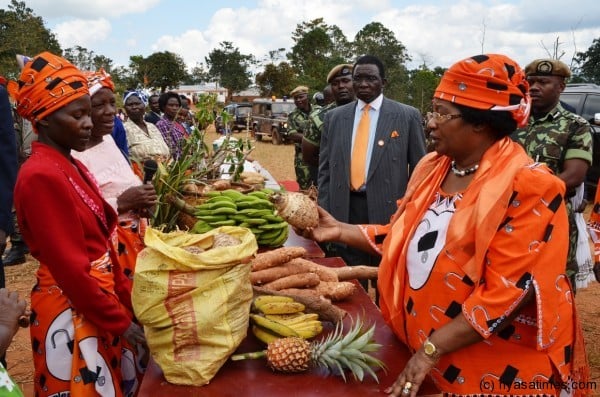 The President interacts with local farmers in Nkhata Bay as she samples some of the farm produce