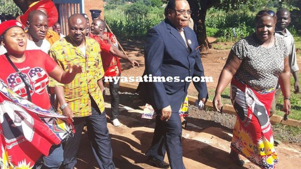 Uladi Mussa (in suit) arriving at police station