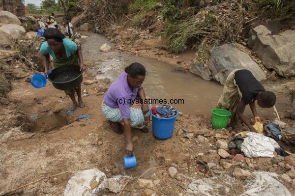 Women wash clothes in a stream caused by flood waters in a suburb of Malawi's commercial city Blantyre on January 19, 2015 ©Amos Gumulira (AFP)